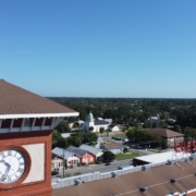 Historic brick clock tower with American flag and lightning protection system on flagpole overlooking downtown area