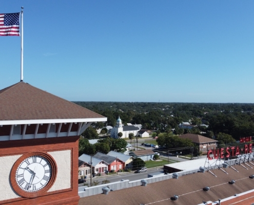 Historic brick clock tower with American flag and lightning protection system on flagpole overlooking downtown area