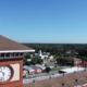 Historic brick clock tower with American flag and lightning protection system on flagpole overlooking downtown area