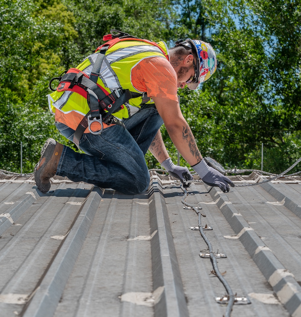 LPI-certified installer carefully mounting lightning protection components on historic building