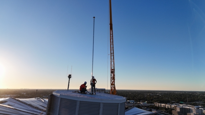 Crane lifting custom lightning protection mast inside Tropicana Field dome
